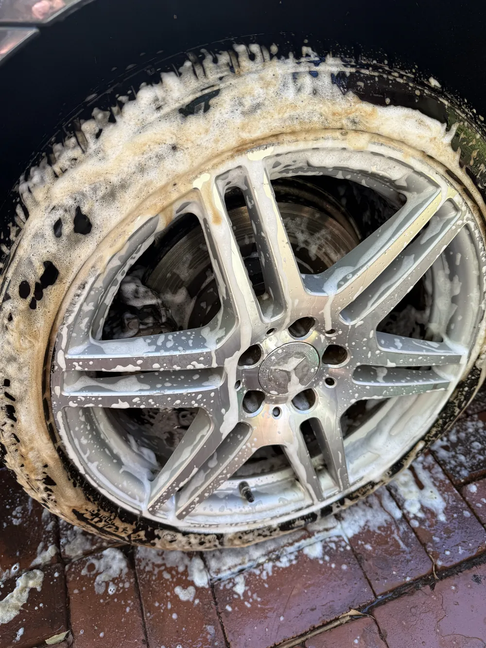 Alloy wheel mid-clean, covered in cleaner and brake dust