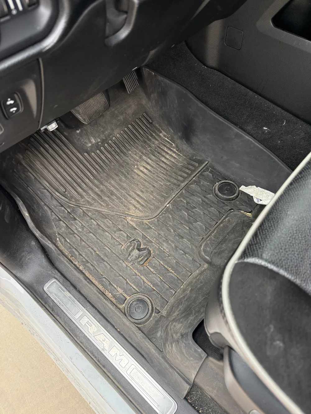 Driver's floor mat before — caked in dried mud